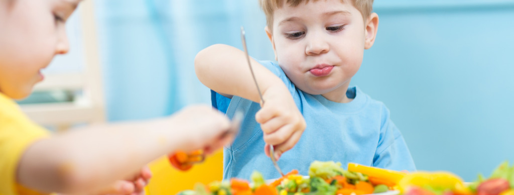 Lapset syövät vihanneksia päiväkodissa tai kotona.